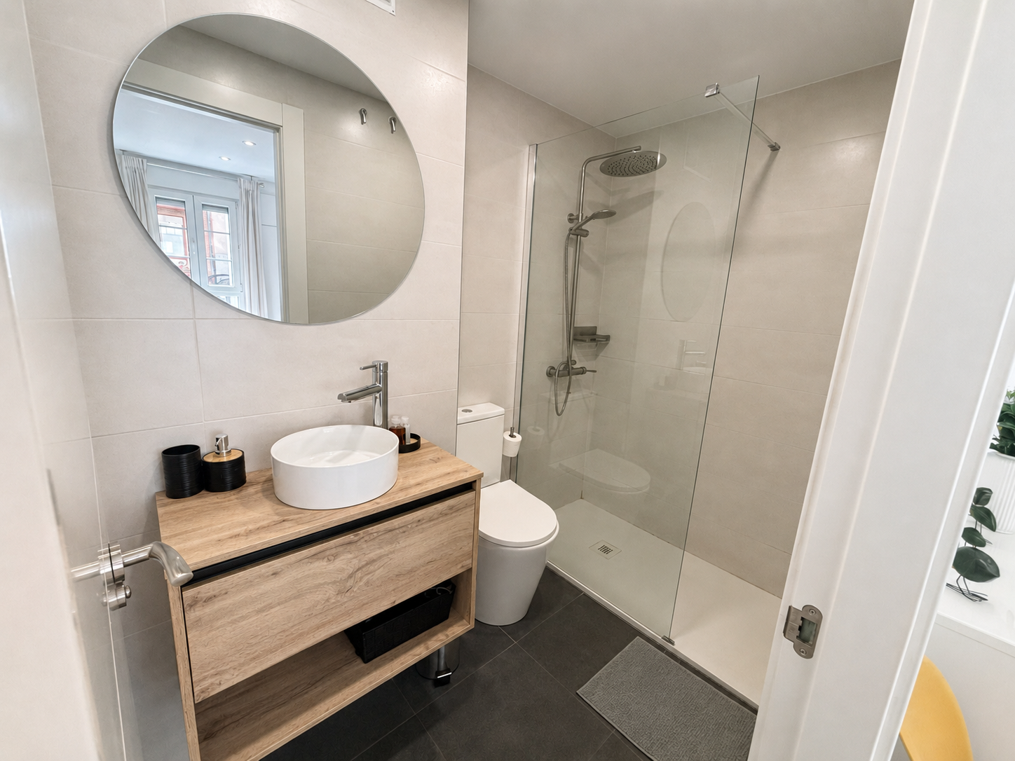 Baño reformado con mueble de madera, lavabo sobre encimera y ducha